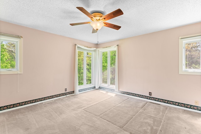 unfurnished room featuring a textured ceiling, carpet, a ceiling fan, baseboards, and visible vents