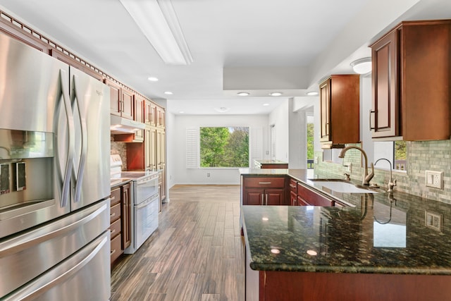 kitchen with range with two ovens, a sink, a peninsula, stainless steel fridge, and under cabinet range hood
