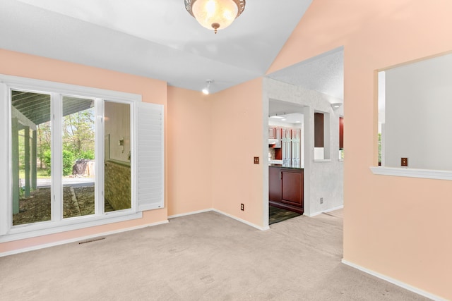 carpeted spare room with visible vents, baseboards, and vaulted ceiling