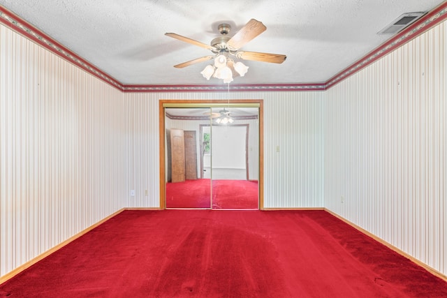 unfurnished room featuring visible vents, ornamental molding, ceiling fan, a textured ceiling, and carpet