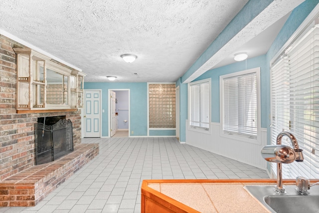 unfurnished living room with light tile patterned floors, baseboards, a brick fireplace, and a wealth of natural light