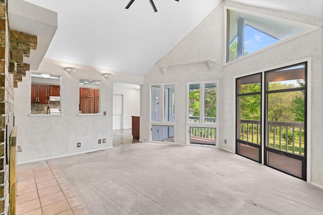 unfurnished living room with light colored carpet, a ceiling fan, baseboards, and high vaulted ceiling