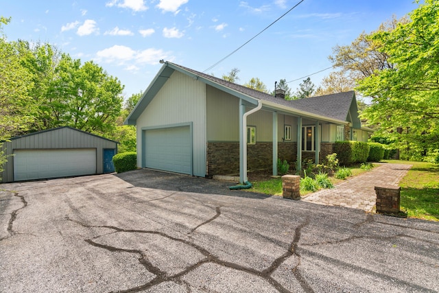 view of side of home with a detached garage, roof with shingles, and brick siding