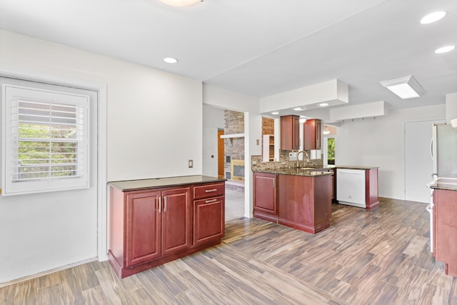 kitchen featuring a brick fireplace, white appliances, wood finished floors, and reddish brown cabinets