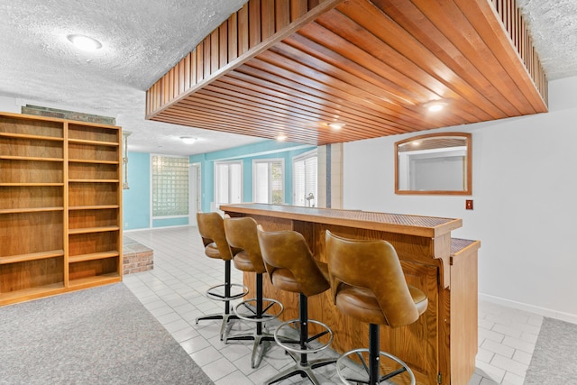 bar featuring baseboards, a dry bar, tile patterned flooring, and a textured ceiling