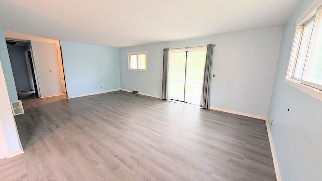 spare room with baseboards, wood finished floors, and visible vents
