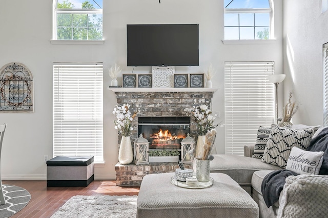 living area with baseboards, a glass covered fireplace, and wood finished floors