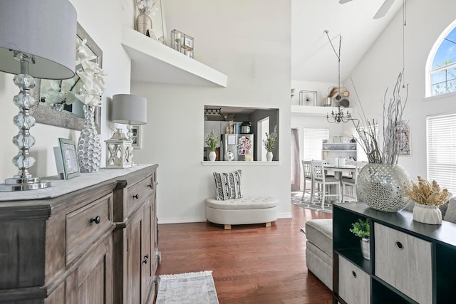 interior space featuring dark wood-type flooring, baseboards, and a towering ceiling