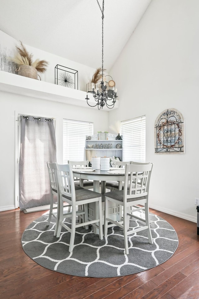 dining space featuring plenty of natural light, wood finished floors, high vaulted ceiling, baseboards, and a notable chandelier
