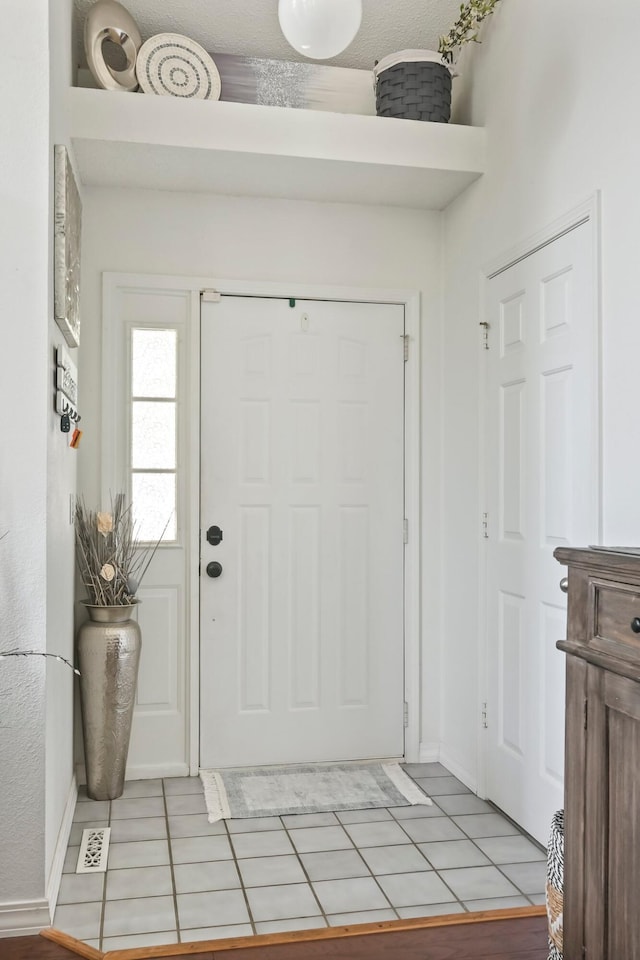 entrance foyer featuring baseboards, light tile patterned flooring, and visible vents