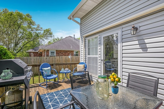 wooden terrace featuring fence, outdoor dining space, and a grill