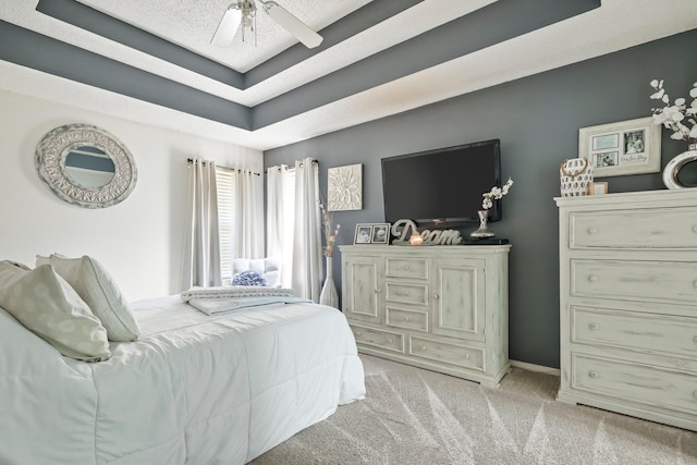 bedroom featuring a raised ceiling, ceiling fan, and light carpet
