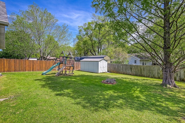 view of yard featuring a playground, an outdoor structure, a fenced backyard, and a storage shed