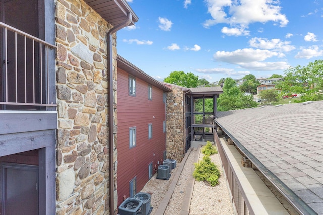 view of side of home with central AC and stone siding