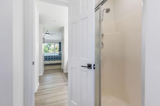 full bath with baseboards, a stall shower, wood finished floors, and connected bathroom