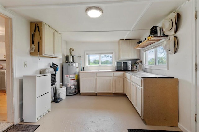 kitchen featuring light countertops, stainless steel microwave, and gas water heater