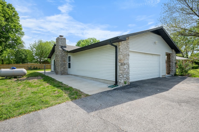 1208 Kemp Dr, Bolivar, MO 65613 - view of home's exterior with driveway, a chimney, fence, an attached garage, and stone siding