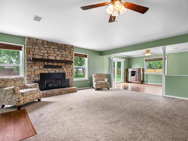 1208 Kemp Dr, Bolivar, MO 65613 - unfurnished living room featuring carpet floors, a stone fireplace, a ceiling fan, baseboards, and visible vents