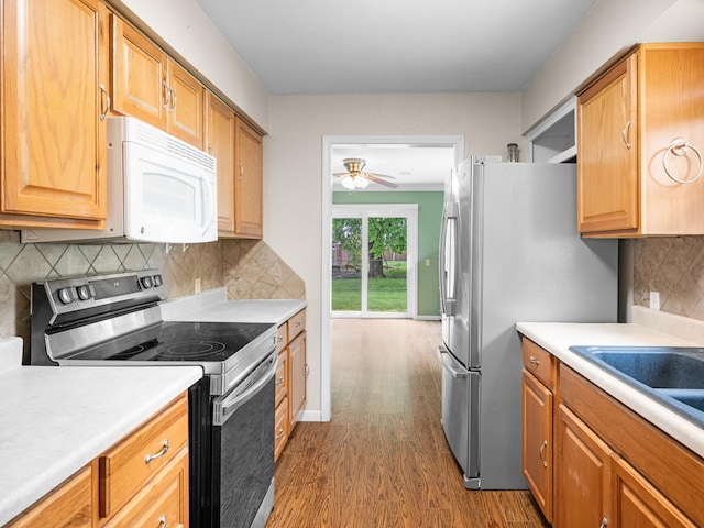 1208 Kemp Dr, Bolivar, MO 65613 - kitchen with dark wood-type flooring, light countertops, a ceiling fan, backsplash, and stainless steel appliances