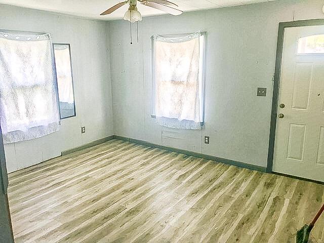 interior space with baseboards, a ceiling fan, and light wood-type flooring