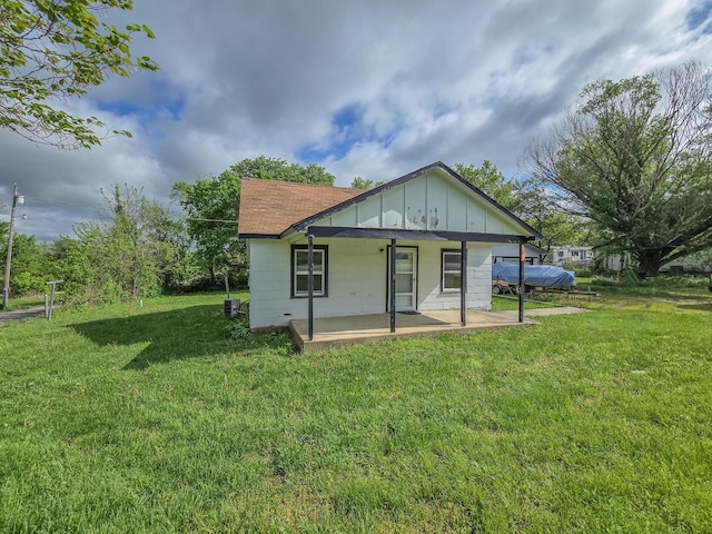 rear view of property featuring a lawn, board and batten siding, and covered porch