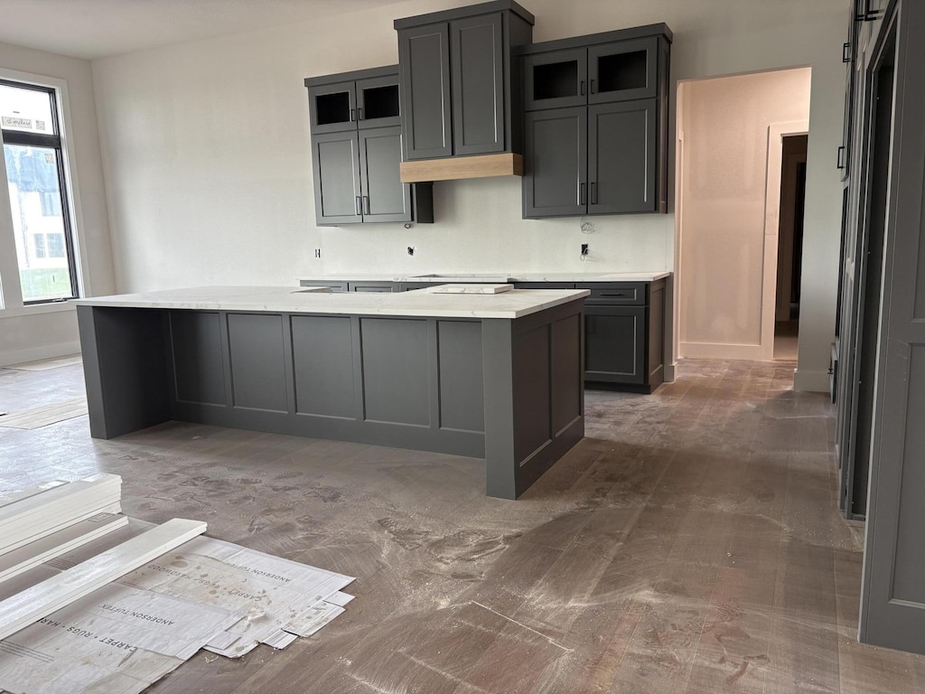 kitchen featuring glass insert cabinets, baseboards, a kitchen island, and light countertops