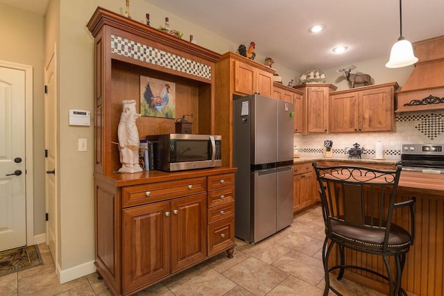 kitchen with decorative backsplash, a kitchen breakfast bar, pendant lighting, brown cabinets, and stainless steel appliances