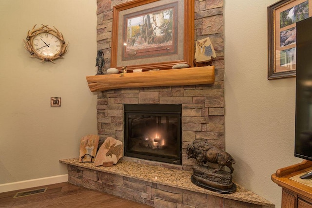 details featuring baseboards, a fireplace, wood finished floors, and visible vents