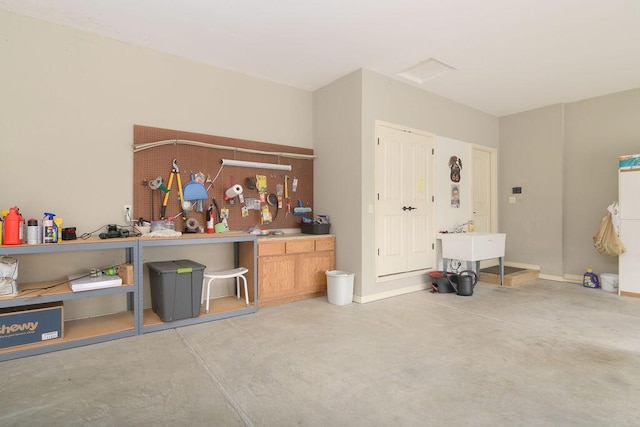 miscellaneous room with baseboards, concrete flooring, and a workshop area