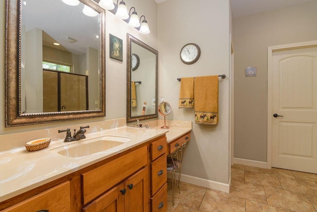 bathroom with baseboards, a shower with shower door, visible vents, and vanity