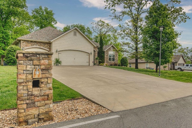 view of front of property with an attached garage, concrete driveway, a front yard, and stone siding