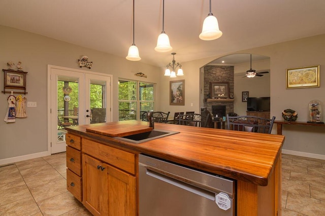 kitchen with a fireplace, stainless steel dishwasher, baseboards, ceiling fan with notable chandelier, and butcher block countertops