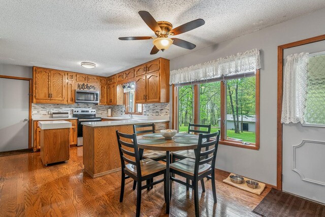 kitchen featuring brown cabinets, appliances with stainless steel finishes, light wood-style flooring, and light countertops