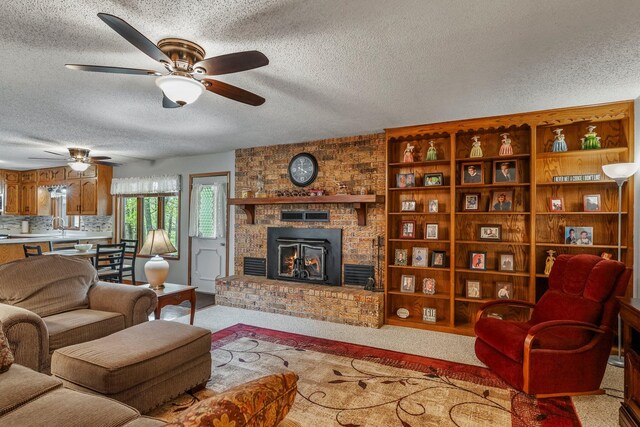 carpeted living area featuring a brick fireplace, a ceiling fan, a textured ceiling, and a sink