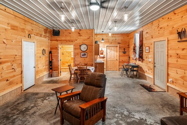 living room with wood walls and unfinished concrete flooring