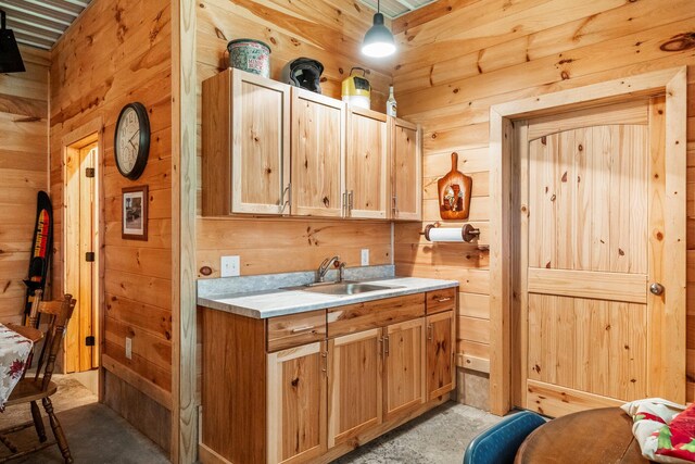 kitchen featuring a sink, pendant lighting, wood walls, and light countertops