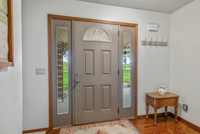 entrance foyer featuring baseboards, a textured ceiling, and wood finished floors