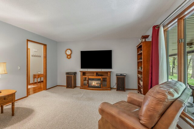living area featuring carpet floors, baseboards, and a glass covered fireplace