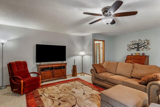 living area featuring baseboards, light carpet, a ceiling fan, and a textured ceiling