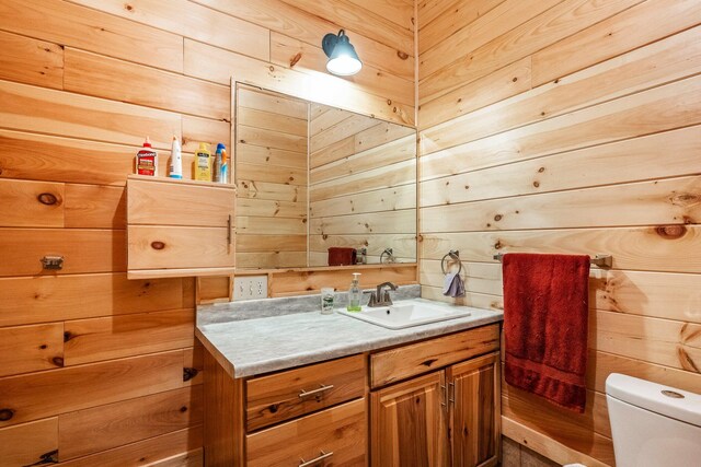 bathroom with wooden walls, toilet, and vanity