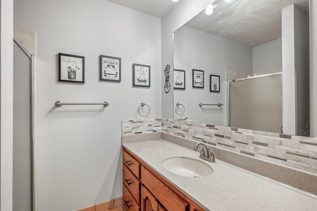 bathroom featuring backsplash, a textured ceiling, a shower stall, and vanity