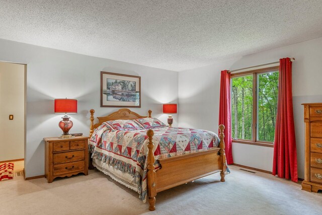 carpeted bedroom with baseboards, a textured ceiling, and visible vents