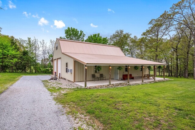 exterior space featuring metal roof, a front yard, a patio area, a garage, and gravel driveway