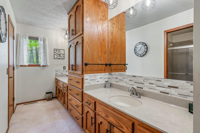 full bath featuring vanity, visible vents, baseboards, a textured ceiling, and backsplash