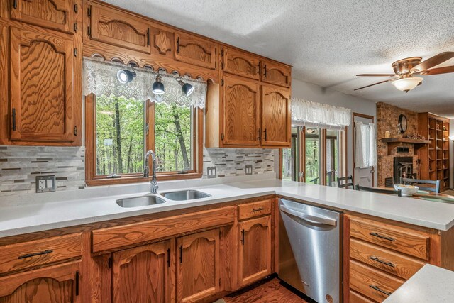 kitchen featuring brown cabinets, a sink, light countertops, a textured ceiling, and stainless steel dishwasher