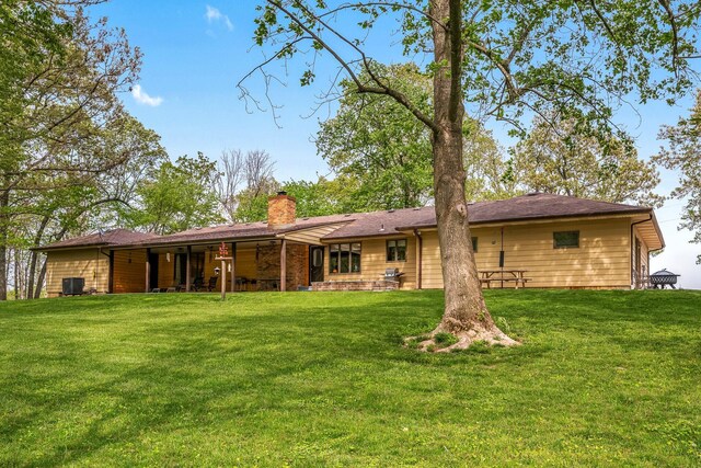 rear view of property featuring a lawn and a chimney