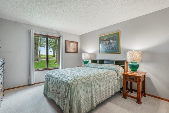 bedroom with a textured ceiling, baseboards, and light colored carpet