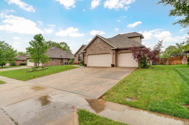 view of front of property with fence, an attached garage, brick siding, a front yard, and driveway