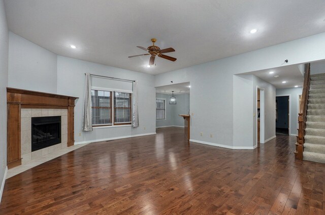 unfurnished living room featuring a fireplace, a ceiling fan, baseboards, wood finished floors, and stairway