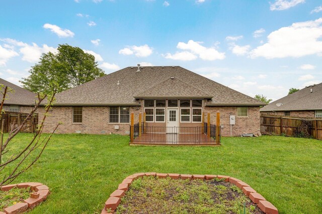 back of house with brick siding, a shingled roof, a fenced backyard, and a yard